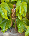 Статуя женщины красится на стуле из бронзы